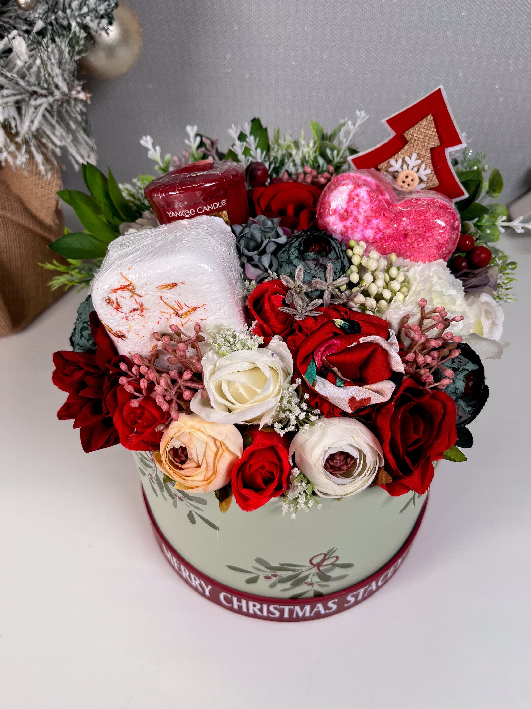 Red mistletoe box filled with artificial flowers and pamper products - bath bomb, shower steamer, yankee candle, satin headband