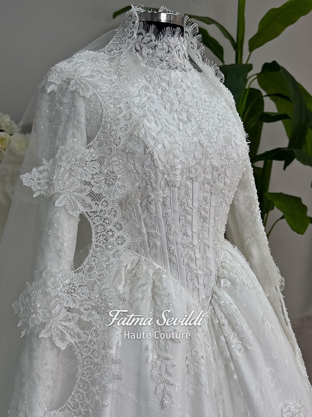 Luxury modest hijab wedding dress ball gown with long sleeves, high neck corset bodice, lace appliqué and included lace veil, photographed in a bridal atelier.