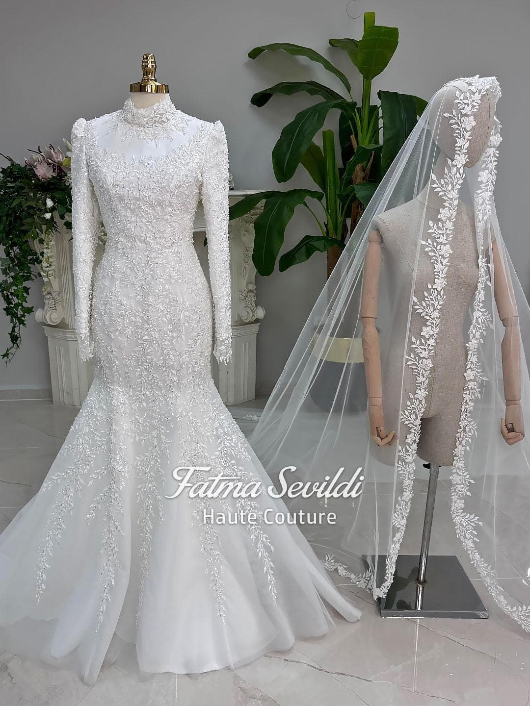 Veiled hijab wedding dress in a modest mermaid silhouette with detachable overskirt, long sleeves and high neck, handcrafted with beaded lace. Includes a matching premium lace veil for a luxury Muslim bridal set.