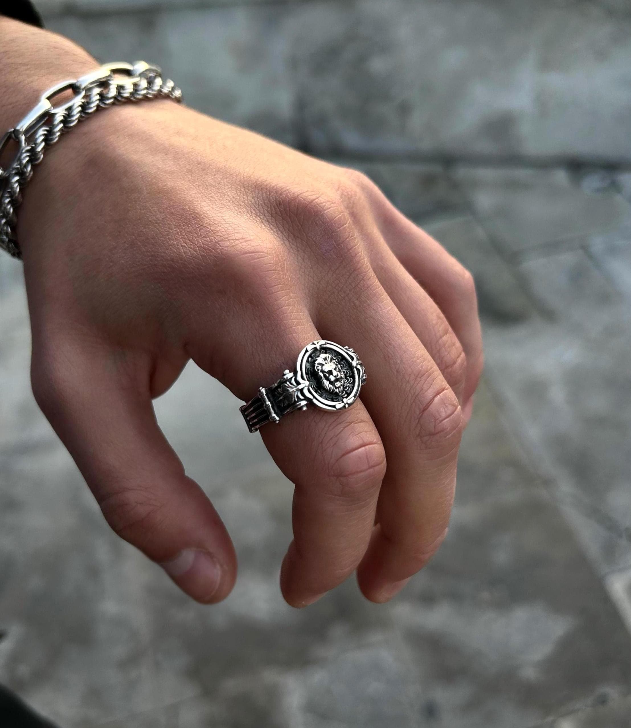 A man's hand wearing a minimalist 925 sterling silver lion signet ring, showcasing its subtle and stoic design as an everyday accessory.