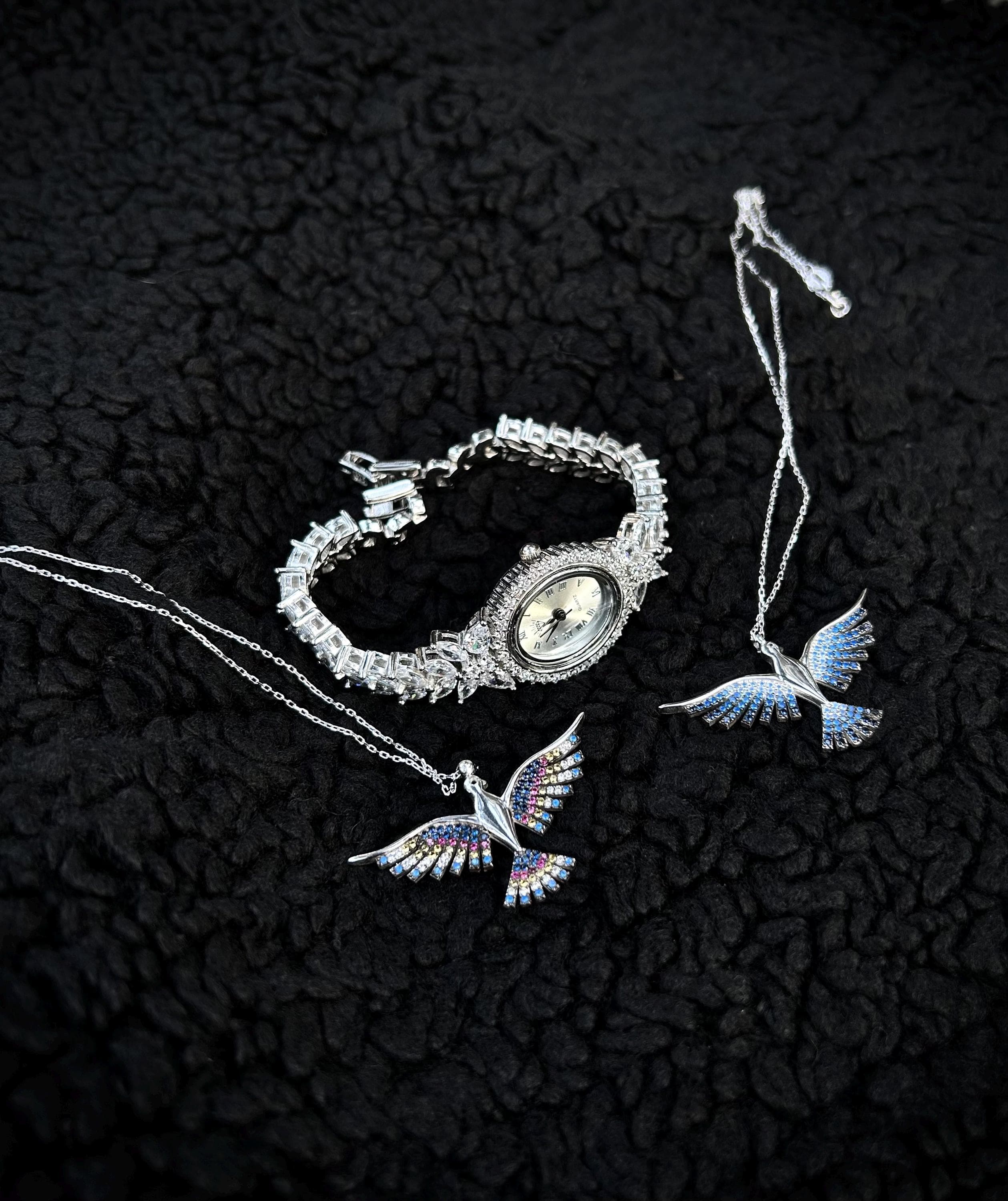 A luxurious rhodium plated women's bracelet watch, handcrafted from sterling silver and iced with shimmering zircon stones. Shown with a Phoenix gift necklace on a black background — ideal for elegant gifting occasions like Mother’s Day.