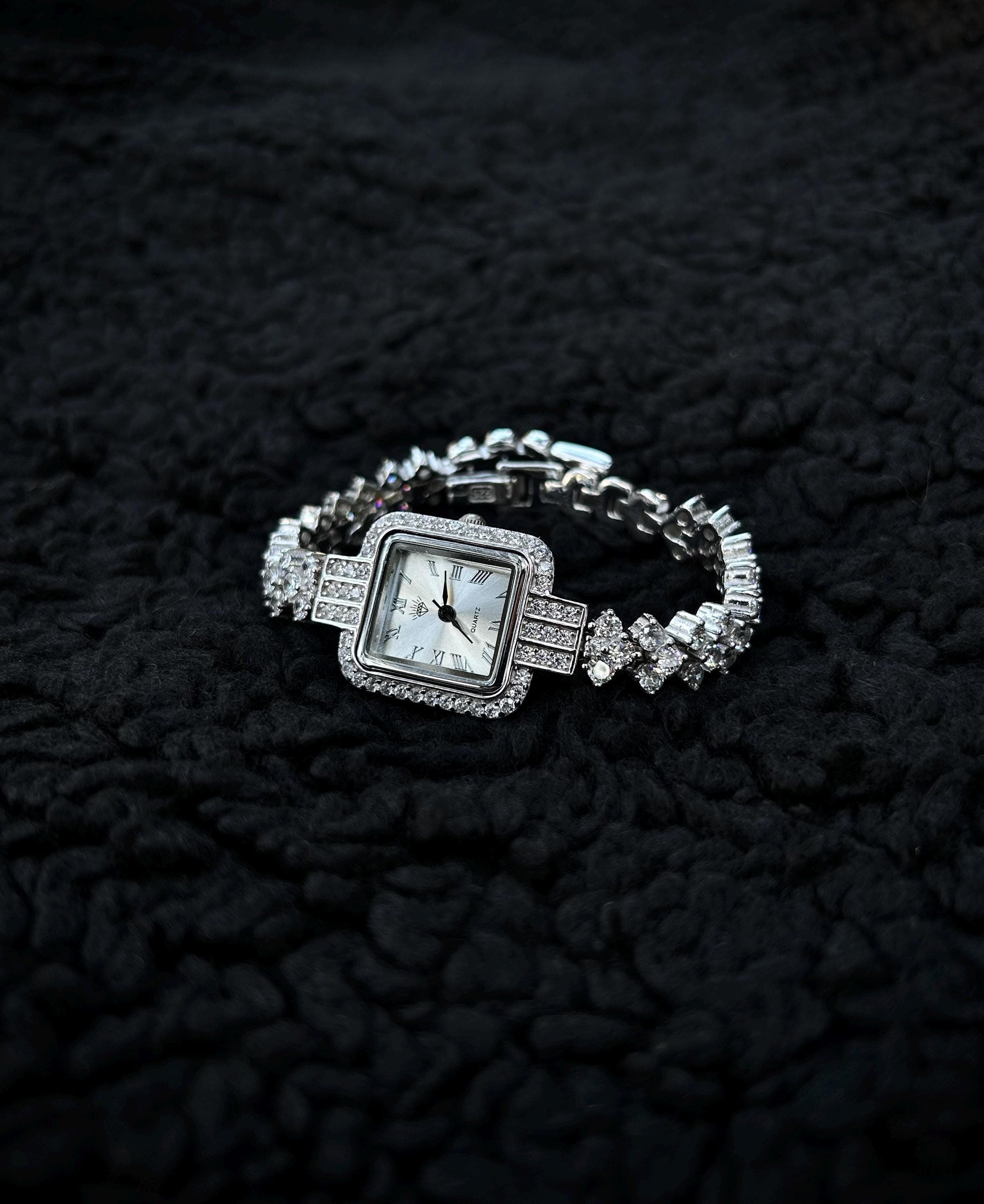 A luxury women's square watch in rhodium plated 925 silver, set with sparkling zircon stones and presented with a Phoenix necklace gift on a nature, elegant backdrop.