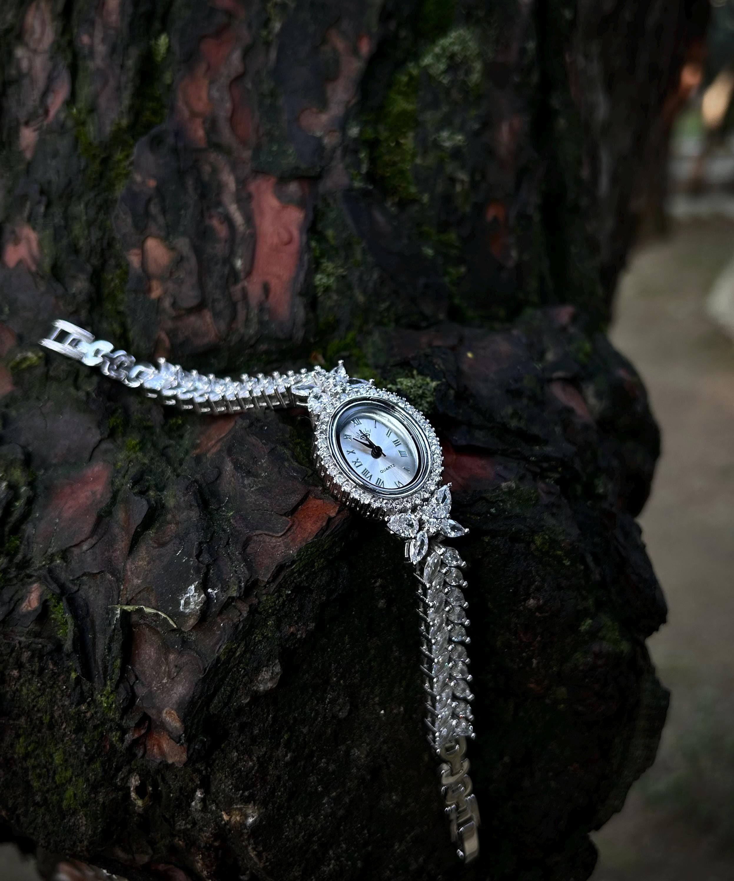 A luxurious rhodium plated women's bracelet watch, handcrafted from sterling silver and iced with shimmering zircon stones. Shown with a Phoenix gift necklace on a black background — ideal for elegant gifting occasions like Mother’s Day.