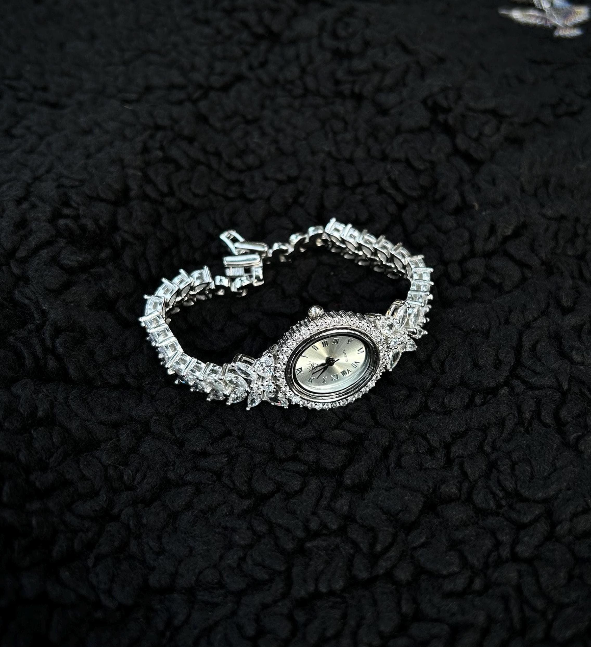 A luxurious rhodium plated women's bracelet watch, handcrafted from sterling silver and iced with shimmering zircon stones. Shown with a Phoenix gift necklace on a black background — ideal for elegant gifting occasions like Mother’s Day.