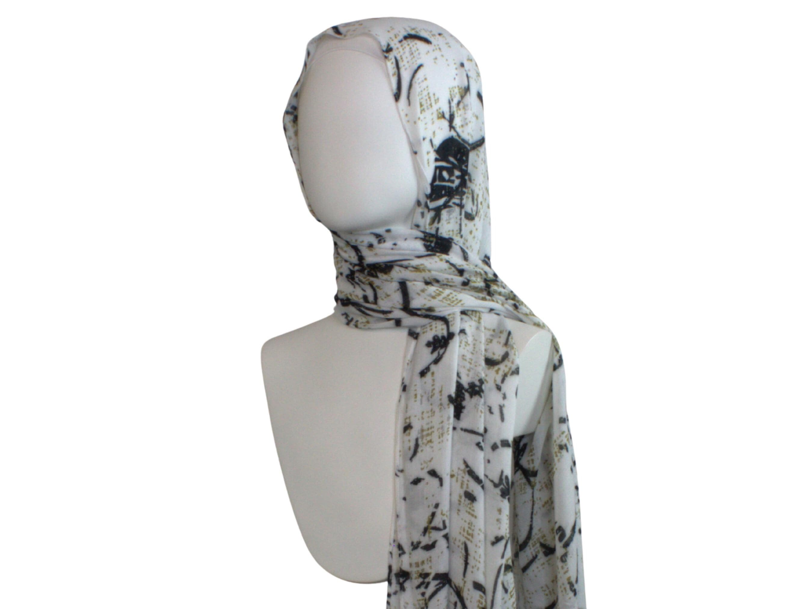 A white bamboo modal printed hijab scarf with a black and gold abstract print. The scarf is draped around a mannequin's neck and shoulders.