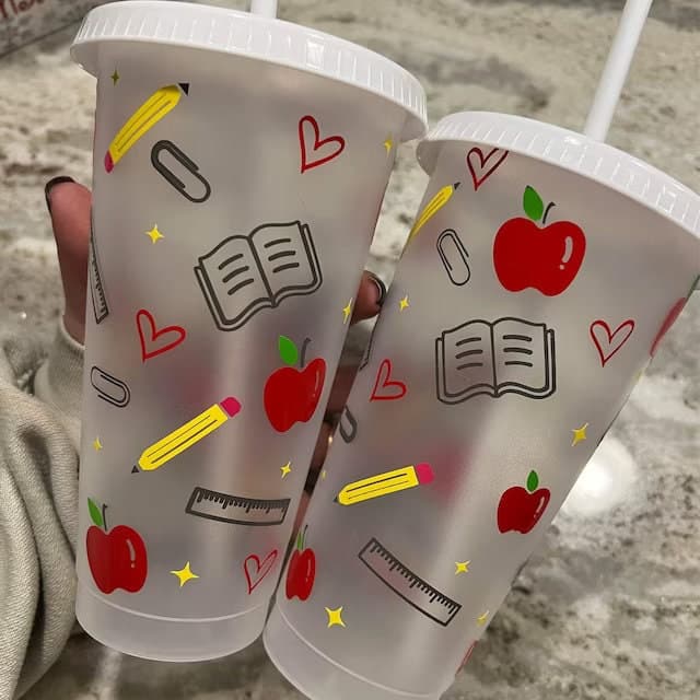 a person holding two cups with drawings on them