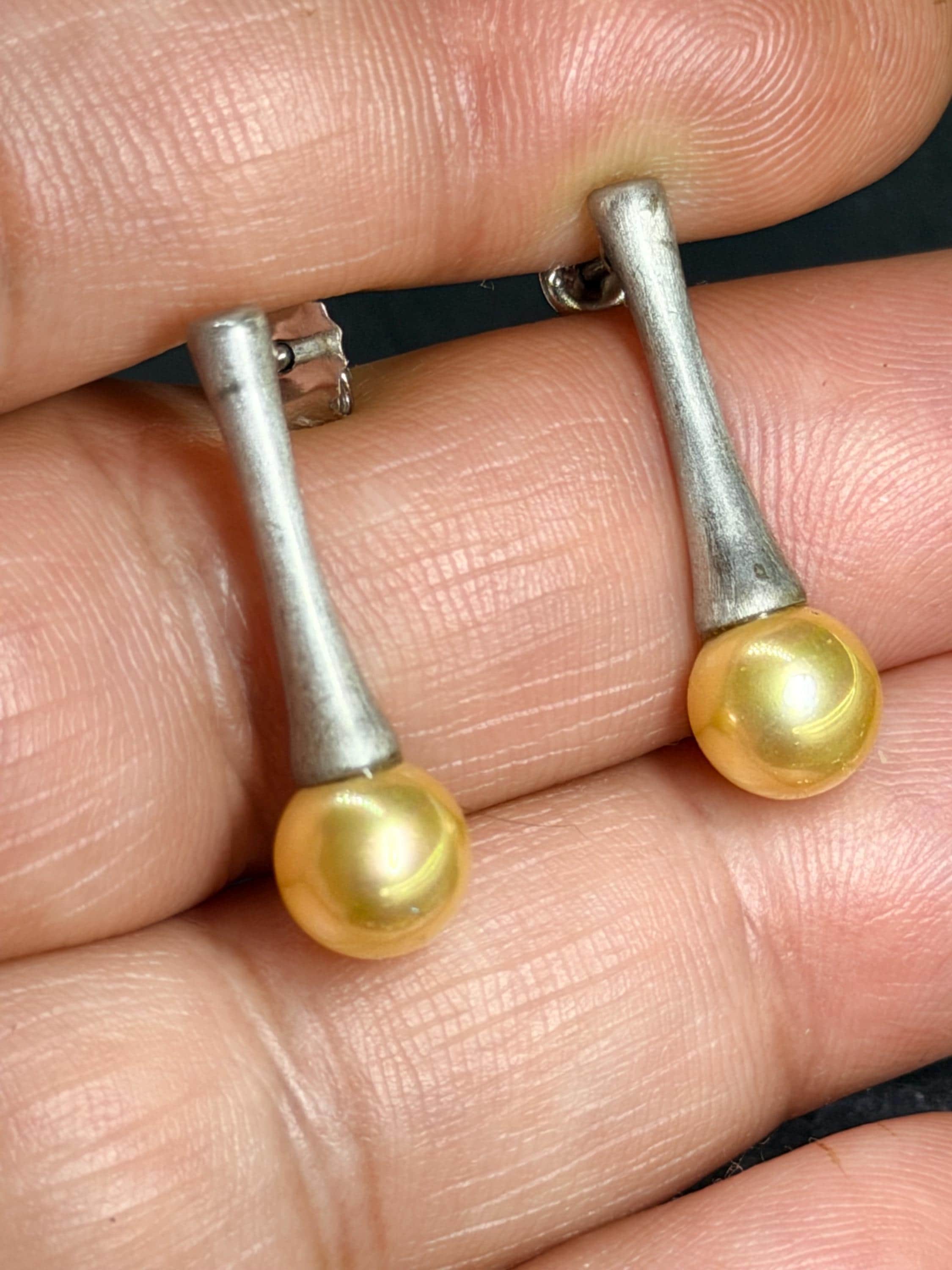Earrings held between fingers for scale and texture