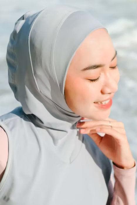 “Lightweight Lycra sport hijab in steel gray, worn by woman at the beach for running and swimming.”