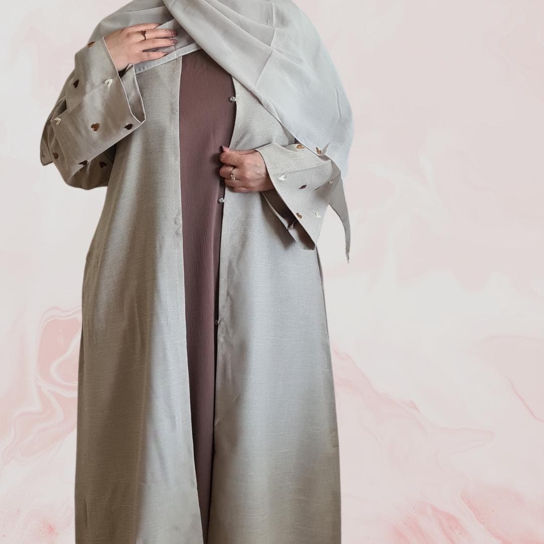 Elegant beige-grey abaya with embroidered heart designs on the sleeves, including hijab and practical pockets – ideal for everyday wear