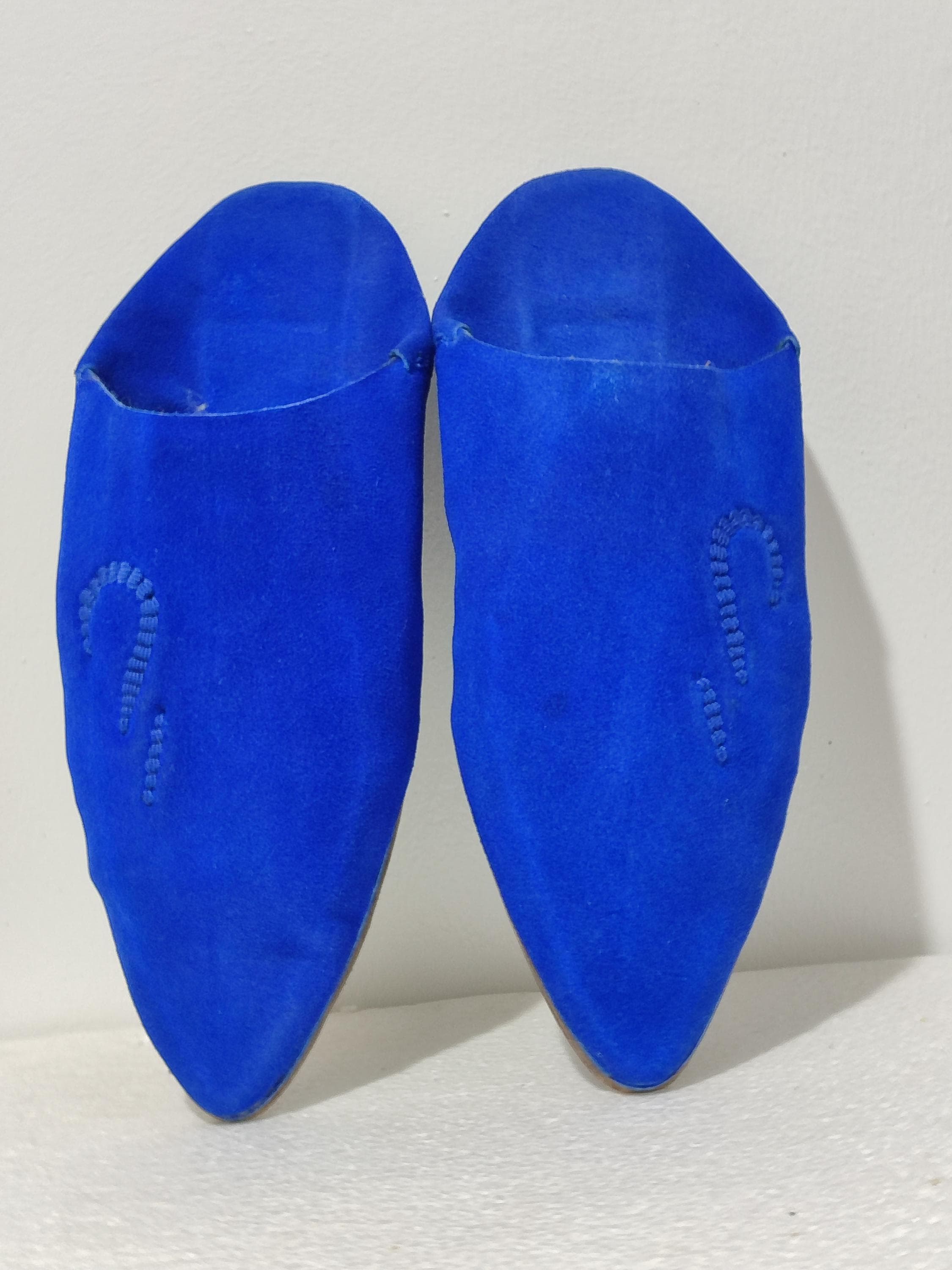 Indulge in the ultimate comfort of these Moroccan leather slippers, meticulously crafted from organic sheepskin. These babouche shoes feature a plush interior lining and durable leather exterior, creating the perfect handmade babouche experience. The Moroccan slippers boast a classic mule silhouette with elegant embroidery accents, blending traditional footwear with contemporary style. Ideal as women's shoes or unisex home footwear, these leather babouches mold to your feet over time.