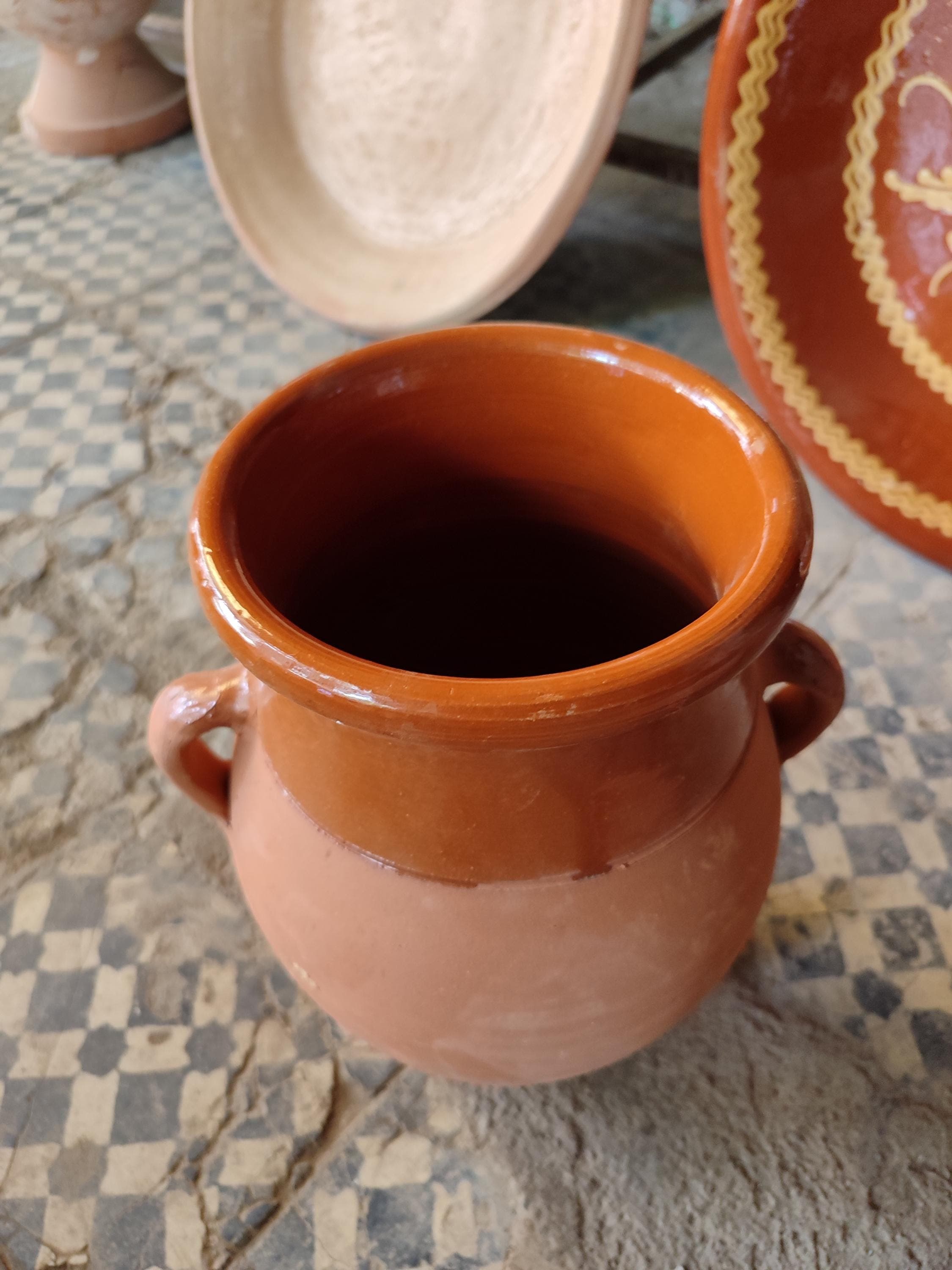 Our Moroccan tanjia is meticulously crafted from high-quality ceramic, designed specifically for the slow-cooking methods of Marrakech cuisine. This terracotta dish features the characteristic narrow opening that helps intensify flavors during the long cooking process. The unglazed interior develops a natural patina over time, enhancing your tanjia dishes with each use. Perfect for preparing traditional Moroccan lamb or beef recipes with aromatic spices.