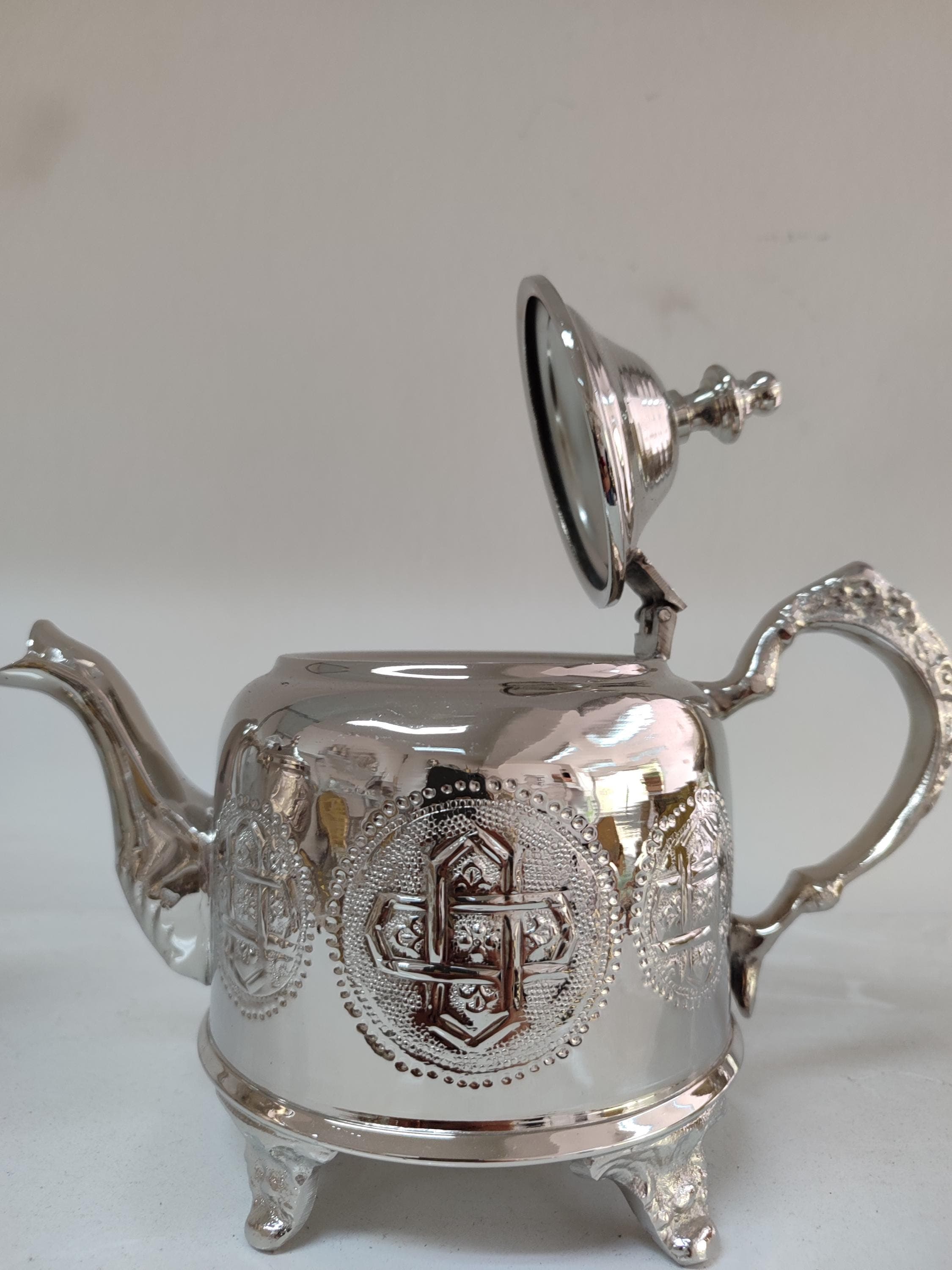 This impressive silver teapot in Moroccan style makes a dramatic statement for tea service. The X large capacity is perfect for gatherings, crafted from high-quality brass with a brilliant silver plating. Every inch of this handmade teapot features meticulous engraved traditional patterns, showcasing exceptional Moroccan craftsmanship. The elegant curved spout ensures perfect pouring, while the ornate handle stays comfortably cool.
