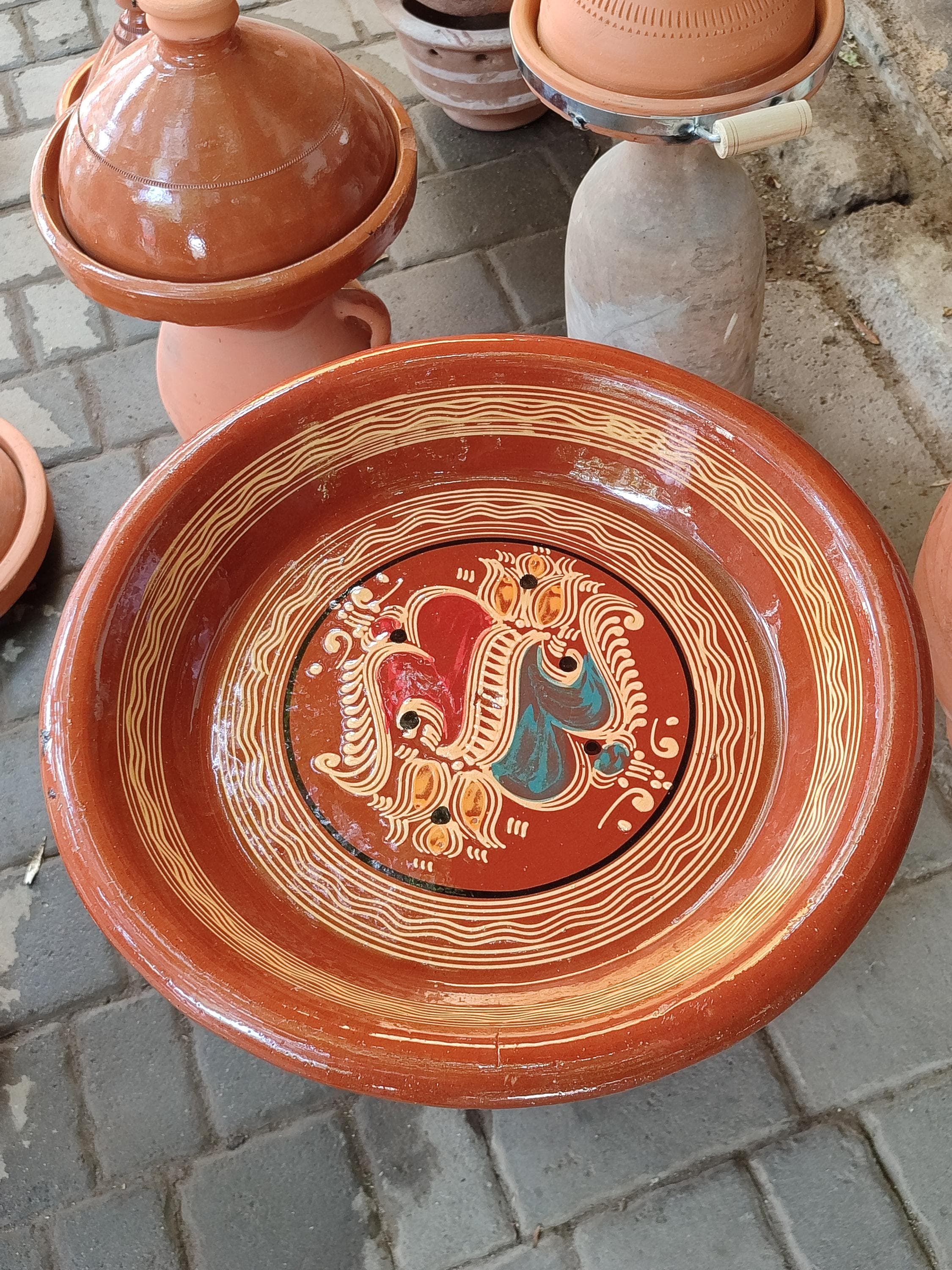 Elevate your table setting with this exquisite Moroccan bowl, a perfect fusion of rustic charm and elegant detail. This boho ceramic bowl features a beautiful silver filigree accent, showcasing the renowned Moorish ceramic artistry of Fez pottery. The intricate patterns and vibrant colors make it more than just a dish; it's a piece of collectible pottery and Moroccan wall art. Use it as a fruit bowl, a unique couscous bowl, or simply as a stunning decorative object.
