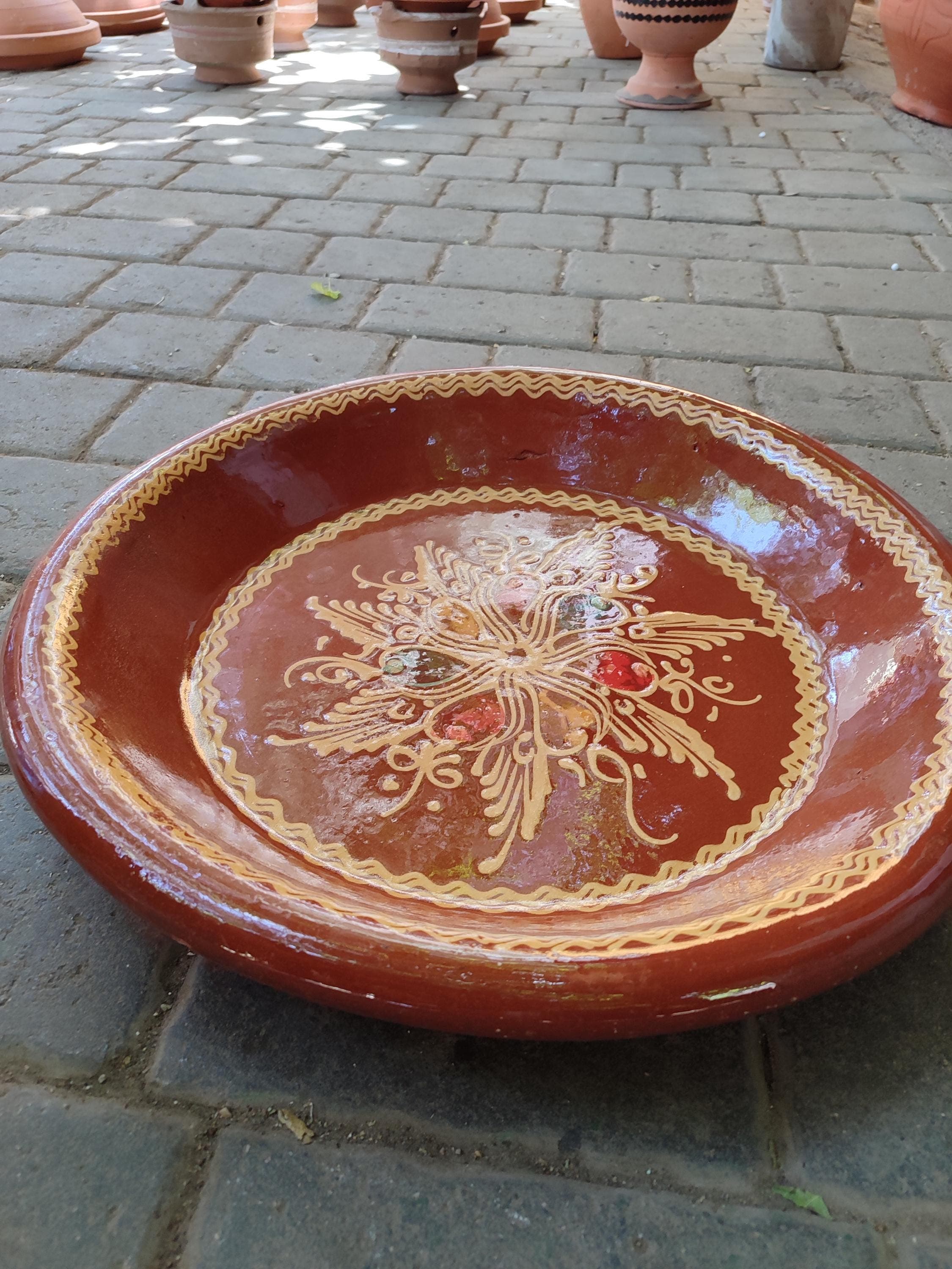 Elevate your dining experience with this expansive clay couscous plate. This Moroccan Kesriya is not only a beautiful serving plate but also a versatile cooking vessel. The unglazed, porous nature of the terracotta clay helps to regulate temperature, keeping your couscous, salads, or bread warm and fresh throughout your meal. Its generous 35cm size makes it ideal for family gatherings, allowing you to present a central dish for 8 people with authentic flair.