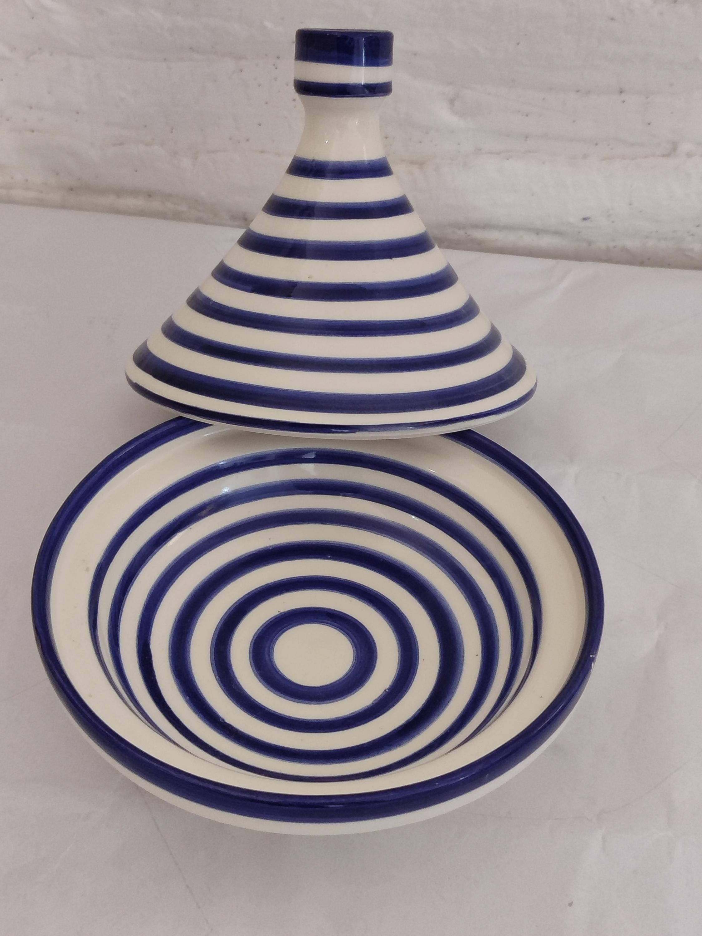 Our extra-large handmade clay tagine (14" diameter) is perfect for entertaining guests with authentic Moroccan tagines. Crafted by skilled artisans using centuries-old techniques, this decorative tagine doubles as beautiful Moroccan dinnerware when serving. The unglazed clay tagine pot naturally enhances flavors during slow cooking, while the iconic conical lid circulates steam perfectly. Features traditional geometric patterns in authentic blue and white colors.