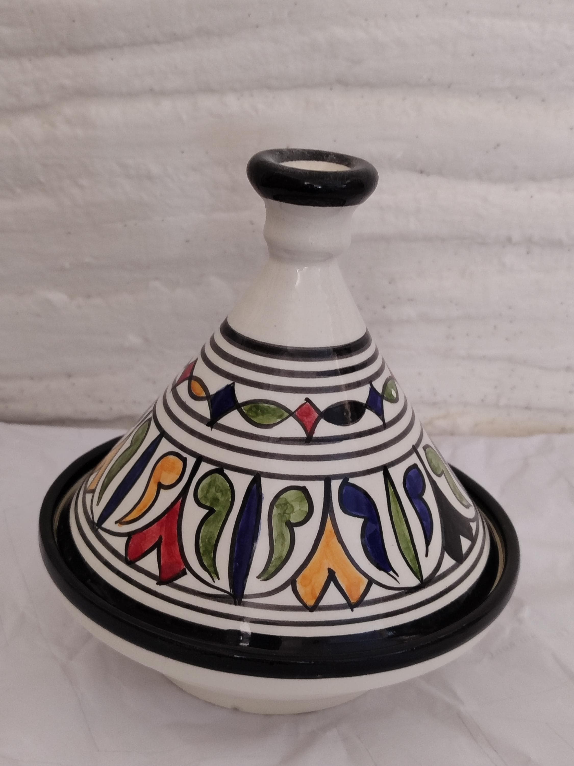 Vibrant Hand-Painted Moroccan Ceramic Tagine - Stunning Home Decor 
Elevate your space with this exquisite decorative tagine, a true piece of Moroccan artistry. This hand-painted tagine is brought to life with vibrant, colorful traditional Berber motifs, each stroke applied by skilled artisans. While it serves as a breathtaking piece of home decor for shelves or sideboards, it is also crafted from authentic ceramic and can be used for cooking.