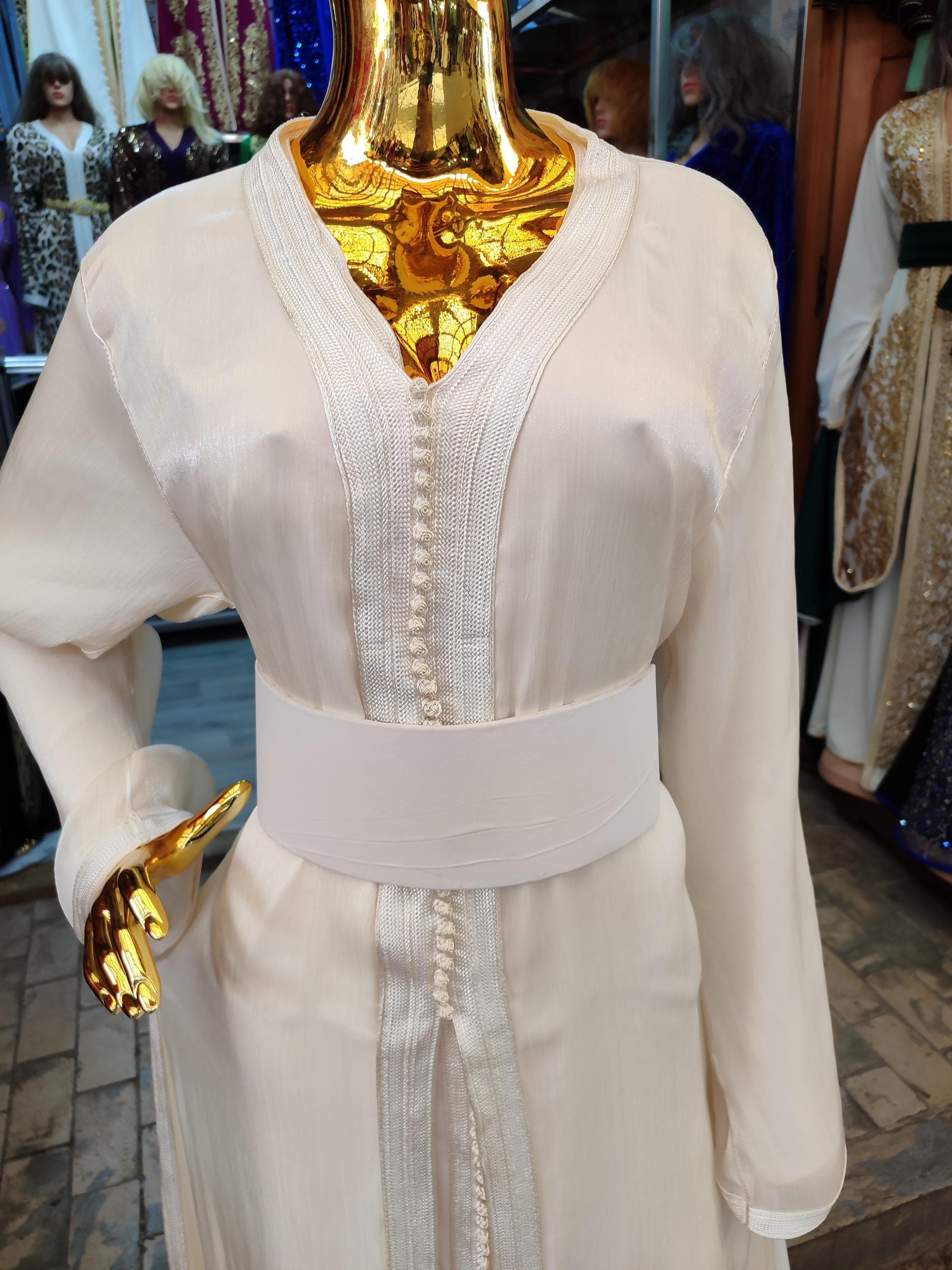 Exquisite moroccan takchita set designed for muslim wedding celebrations and special occasions. This luxurious arabic dress features a matching caftan marocain base layer with ornate overlay, both crafted from fine fabrics with metallic embroidery. The elegant kaftan silhouette flatters all body types while maintaining modesty. Perfect as a nikah dress or for henna ceremonies, this set comes with an optional belt to accentuate the waist.