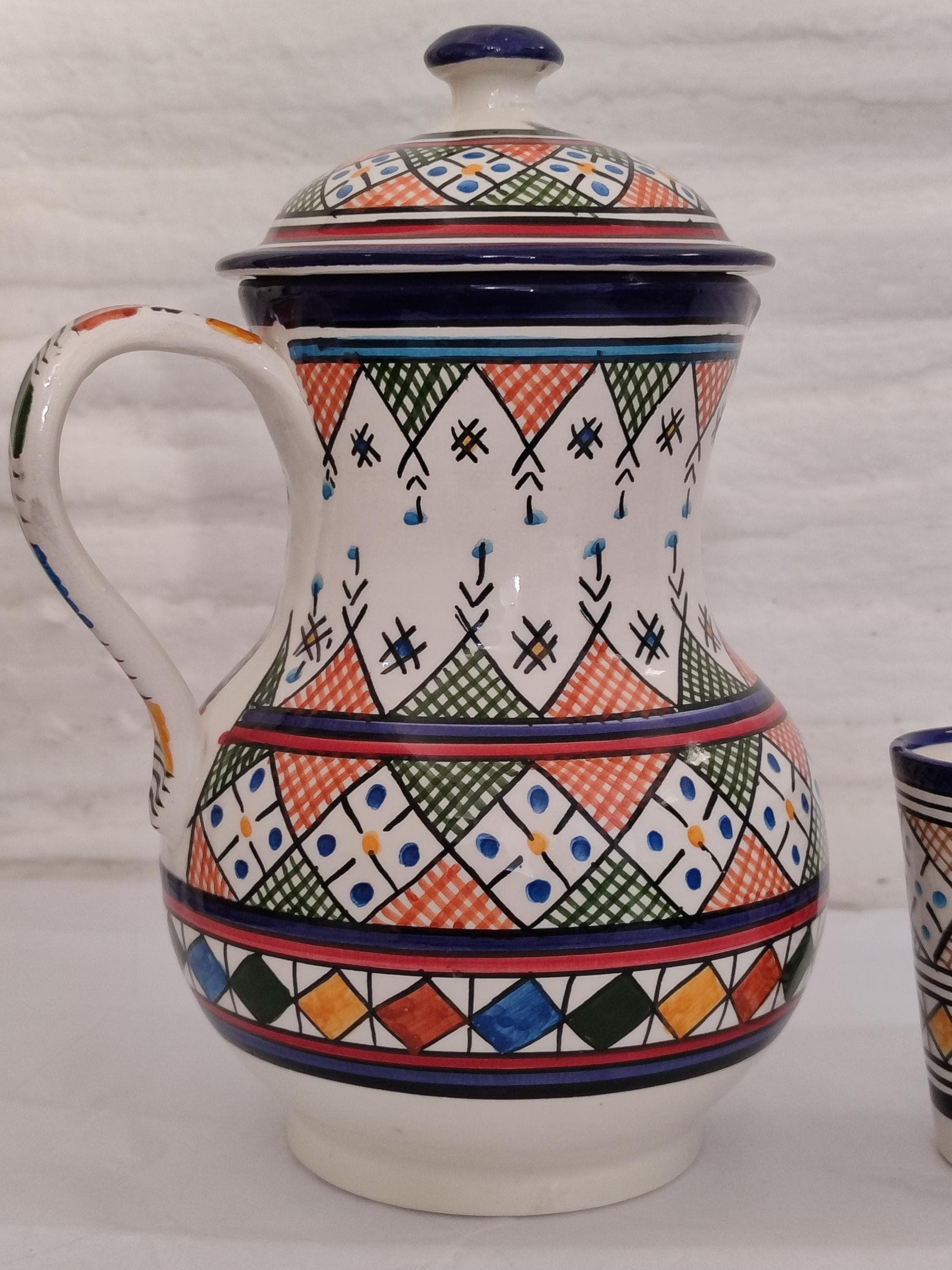 Elevate your space with this vibrant colorful ceramic set, a masterpiece of authentic Moroccan art. Each handcrafted ceramic pitcher is a unique work of art, featuring bold, mesmerizing geometric patterns characteristic of Fez ceramics. This handmade carafe is designed to be a statement piece, whether used as a functional traditional water pitcher for serving guests or displayed as exquisite home decor. It embodies the spirit of artisan pottery, making it a memorable