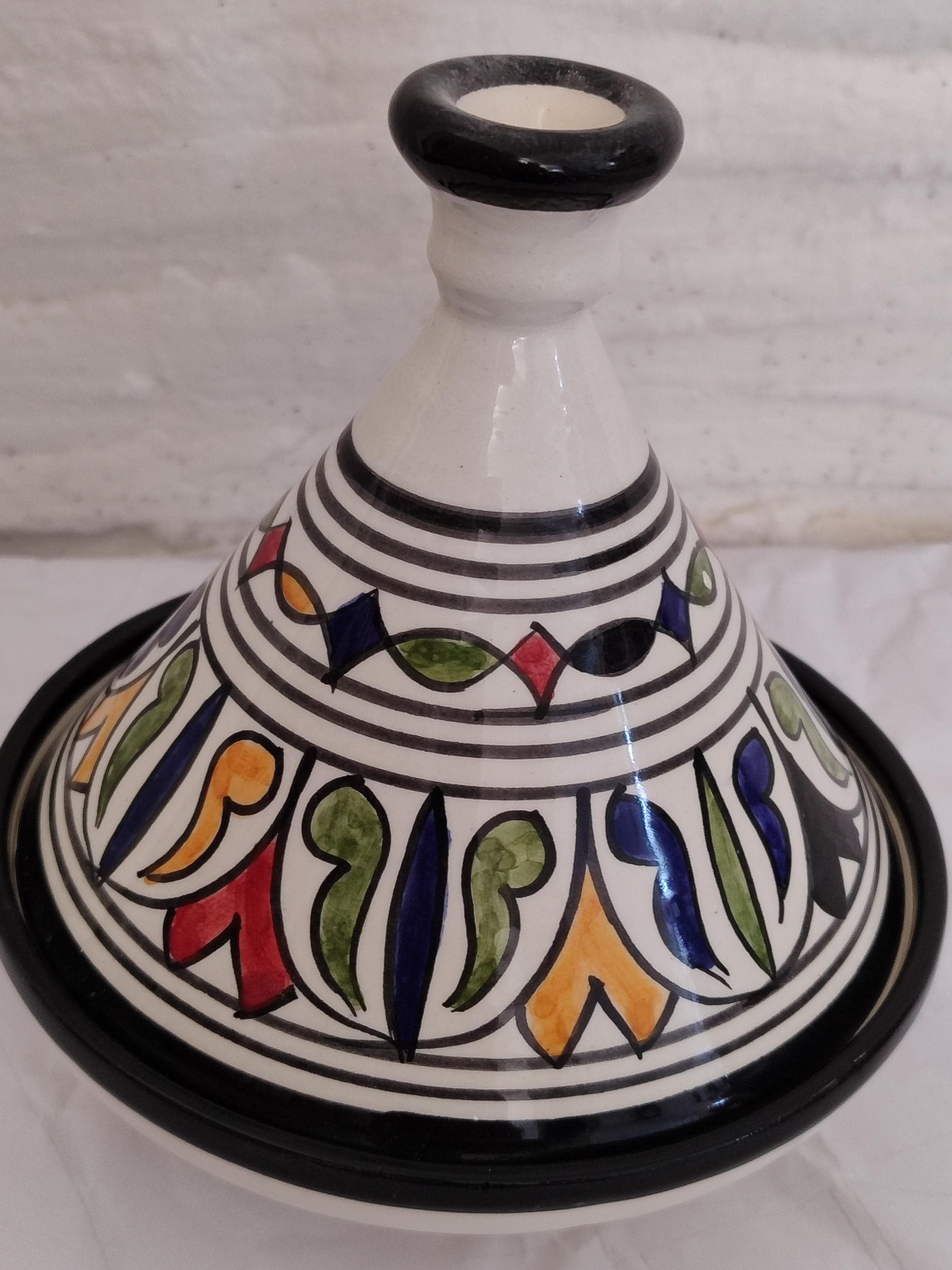 Embrace timeless tradition with this antique tagine inspired by Berber heritage. This handmade clay tagine showcases a rustic, authentic finish and hand-painted symbols that tell a story of Moroccan culture. While it serves as a unique and conversational piece of home decor, it is also fully functional as traditional cookware. Each Moroccan tajine is unique, with slight variations that prove its artisanal origin. This pottery tajine is perfect for authentic Moroccan cookware.