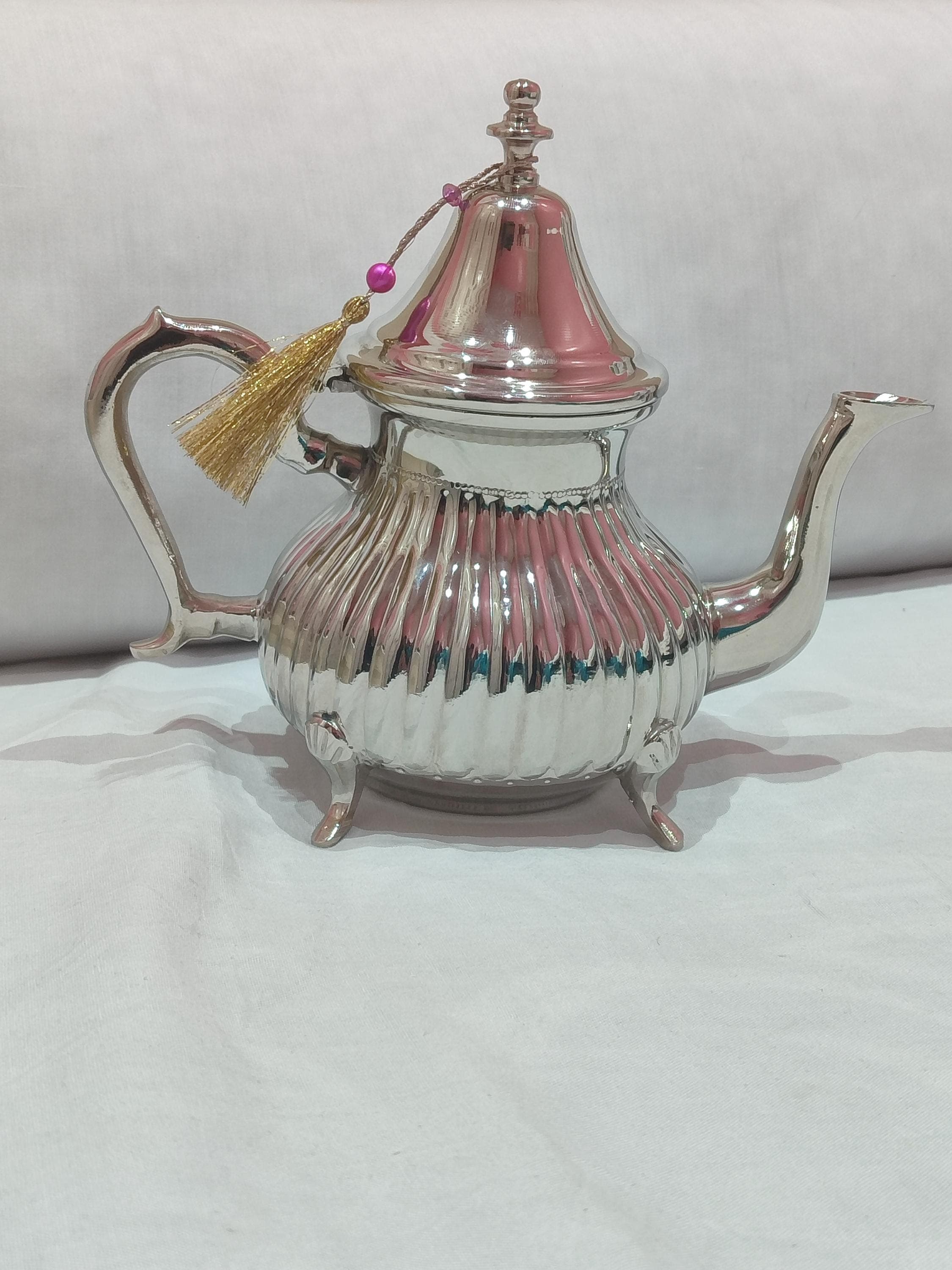 This beautiful antique teapot recreates the classic designs of Moroccan teapot heritage with modern durability. Made from stainless material with a silver brass exterior, it offers both beauty and practicality. The oriental teapot design includes traditional Moroccan motifs and a functional filter for loose-leaf tea preparation. Excellent for brewing aromatic Moroccan mint tea or other herbal infusions, this Arabic teapot brings an authentic tea experience to your home.