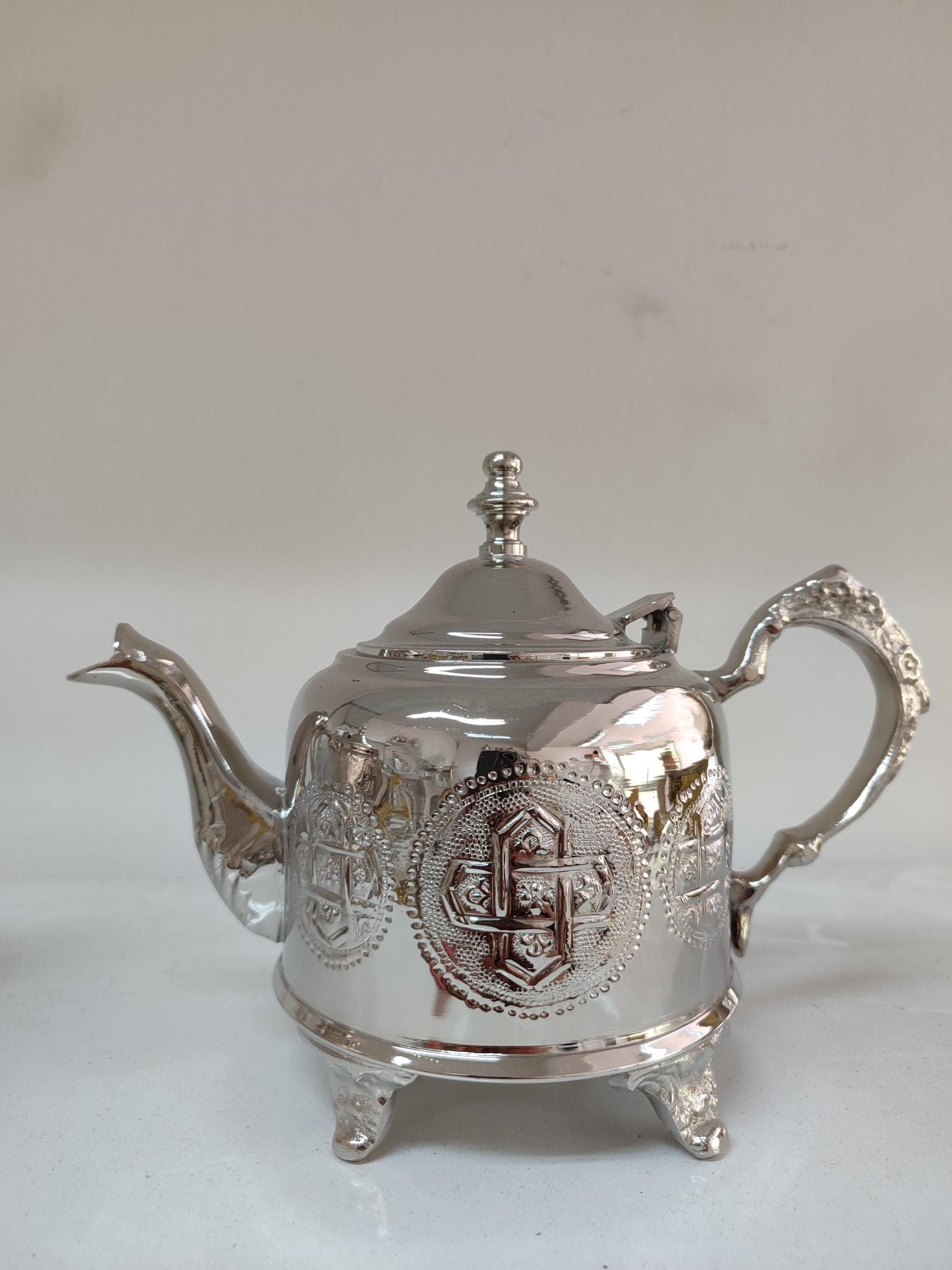 This exquisite Moroccan teapot is crafted entirely by hand from premium brass, showcasing authentic Moroccan decor artistry. The elegant engraved teapot features intricate geometric patterns characteristic of traditional Moroccan metalwork. Perfect for serving mint tea in true North African style, this vintage teapot design combines functionality with stunning home decor appeal. The durable brass construction ensures even heat distribution for optimal tea brewing.
