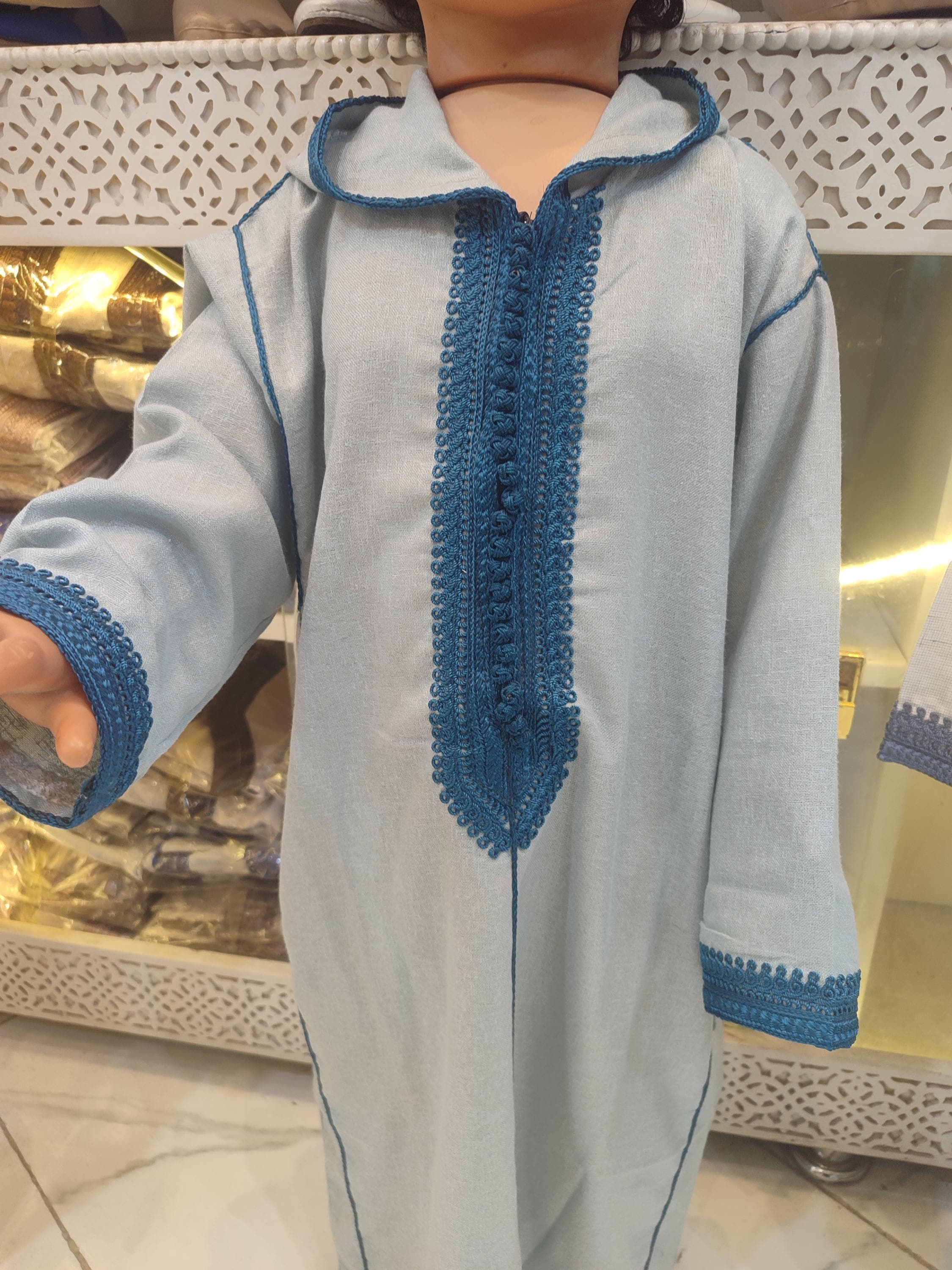 This complete muslim boy clothing set includes a beautifully crafted boys Moroccan jalaba with coordinating accessories for the perfect eid outfit boys. The wool kids caftan centerpiece features the classic hooded jalaba kids design with intricate embroidery and traditional buttons. This ramadan outfit boys ensemble is ideal for eid al fitr 2025 celebrations, family photos, or special gatherings. As an authentic Moroccan traditional dress piece,