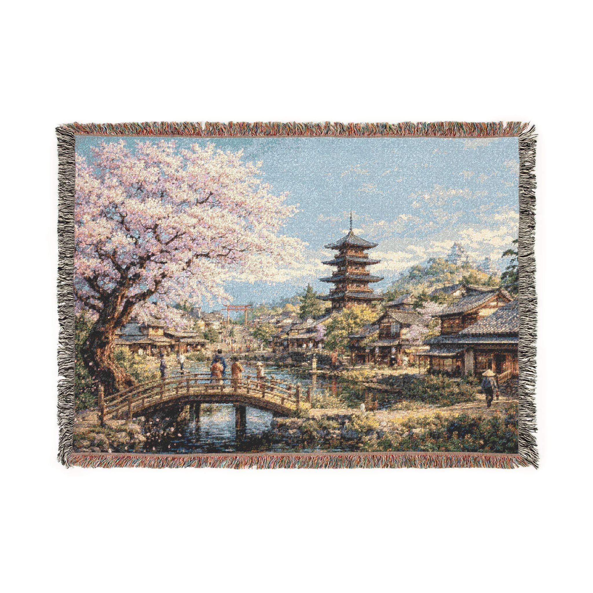 Woven tapestry wall hanging featuring a peaceful Japanese village in spring with a blooming cherry blossom tree, wooden bridge, calm canal, traditional houses, and a tall pagoda beneath a bright blue sky. Scenic sakura wall art with soft pink blossoms, reflective water, and serene old world detail, ideal as a large wall tapestry, decorative throw blanket, Japanese home decor accent, and gift for cherry blossom lovers, spring decor fans, and collectors of tranquil landscape art.