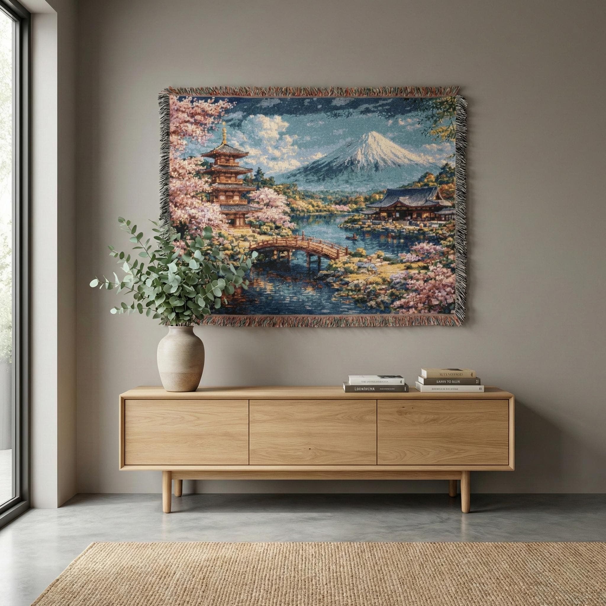 May include: Woven throw blanket featuring a Japanese landscape with a pagoda, bridge, and Mount Fuji. The scene includes cherry blossoms, a lake, and traditional buildings. The blanket has a fringed edge and a detailed, colorful design.